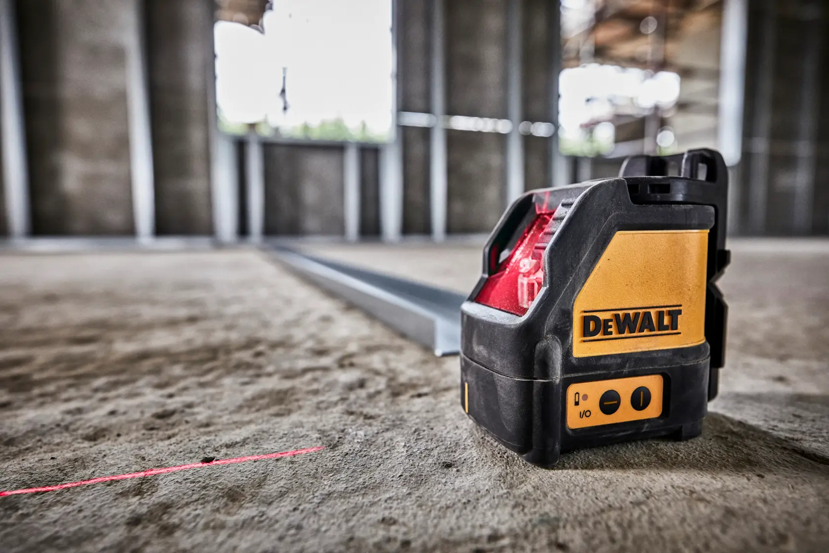Nivel láser DEWALT emite una línea roja en el suelo de obra para mediciones precisas.