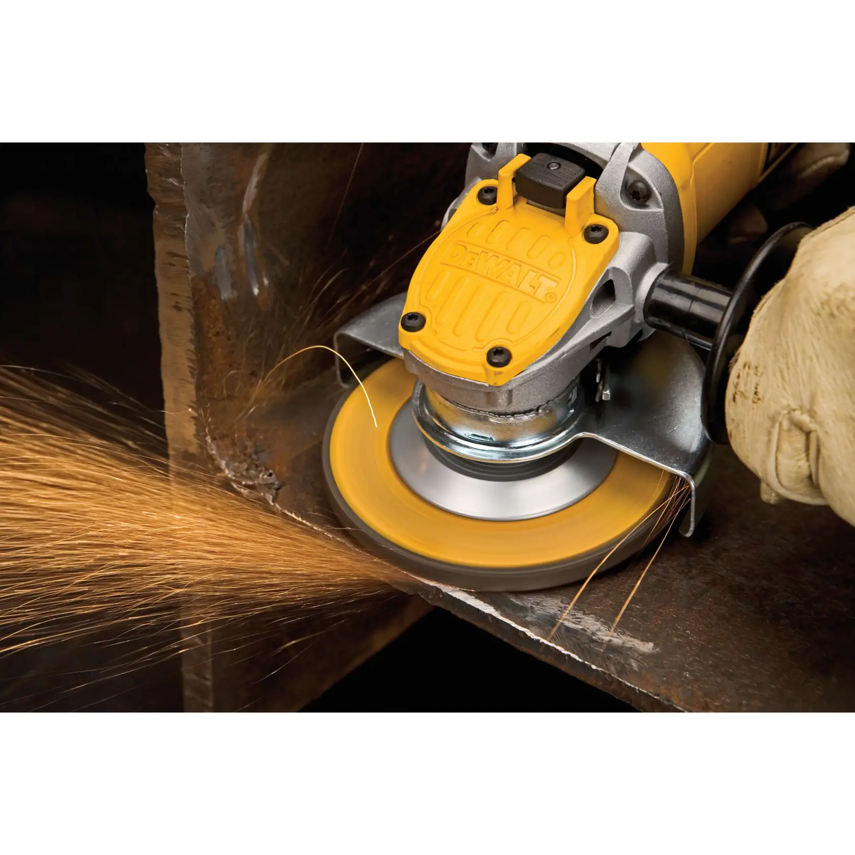 Primer plano de una persona usando una amoladora angular amarilla DEWALT, generando chispas mientras lija el borde de una superficie metálica. La persona lleva guantes protectores.