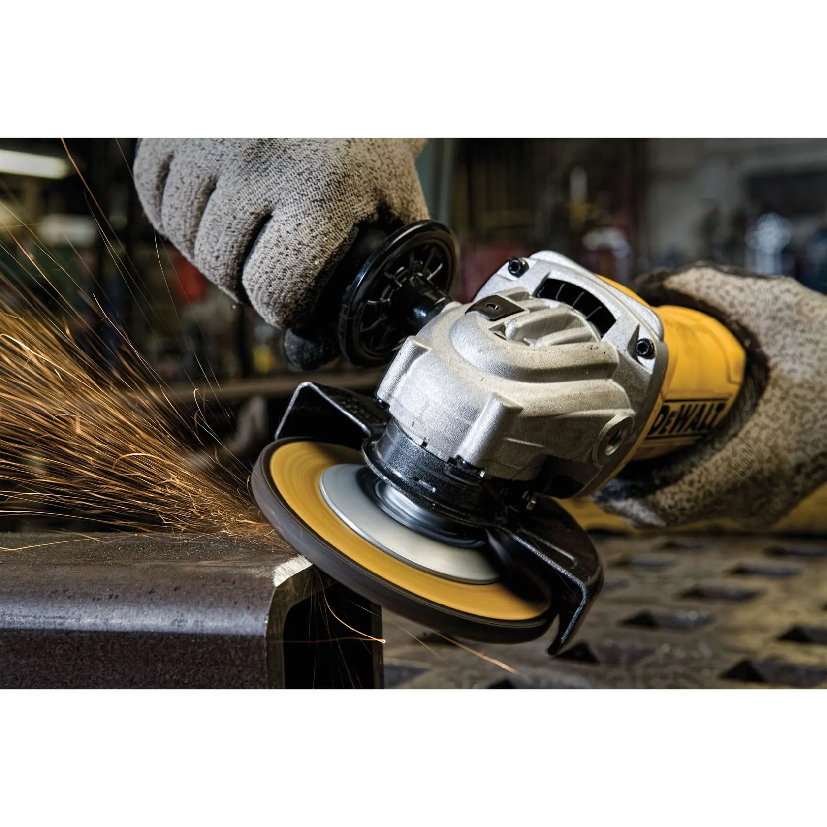 Primer plano de una persona usando una amoladora angular DEWALT para lijar una pieza de metal, con chispas volando. La persona lleva guantes de protección.