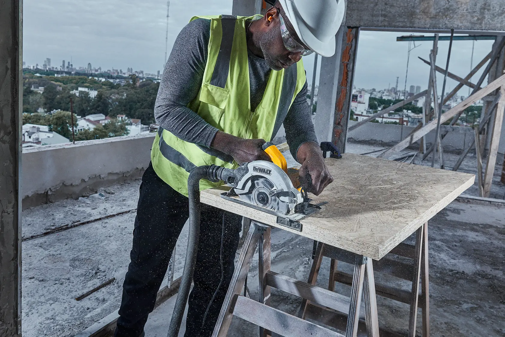 Un trabajador de la construcción con chaleco de seguridad y casco utiliza una sierra circular DEWALT DWE5615 para cortar una tabla de madera en una obra.